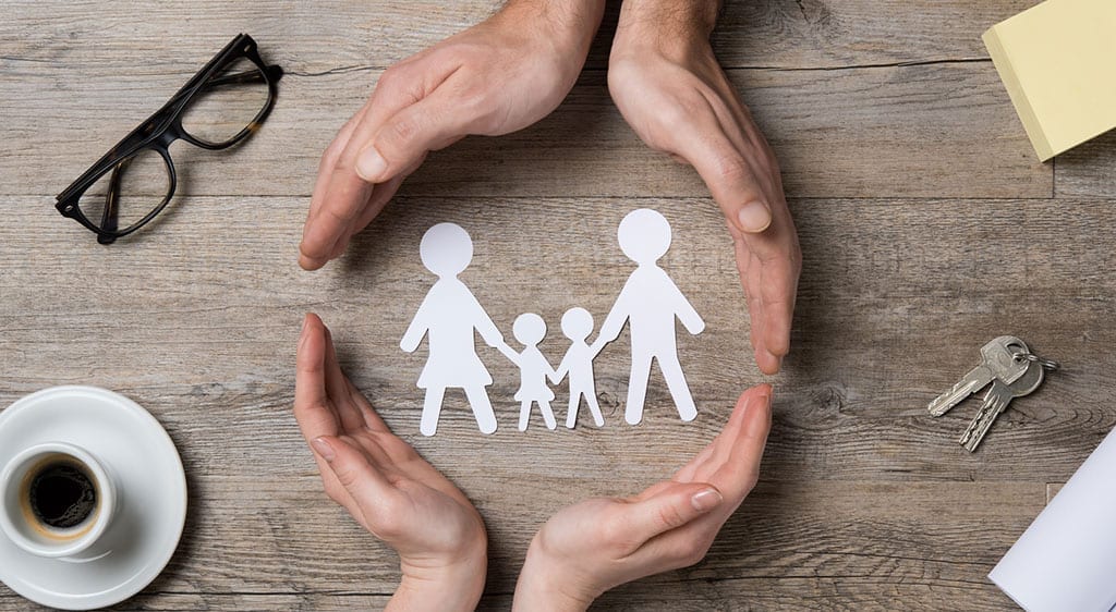 Paper Family Being Protected by Hands