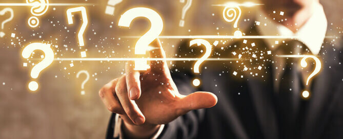 Suited Man Pointing Finger at Question Marks