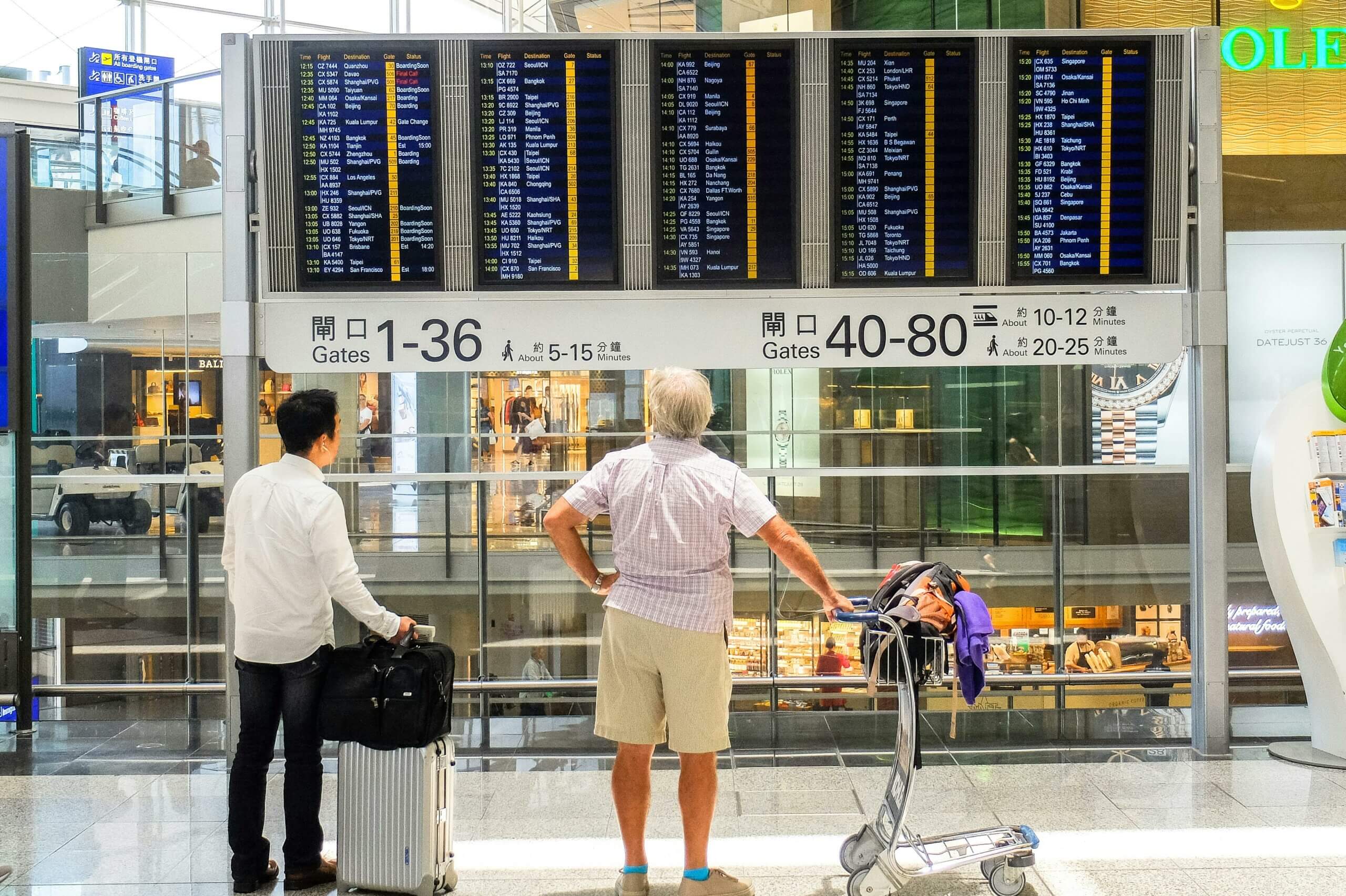 Two men looking at an airport flight schedule