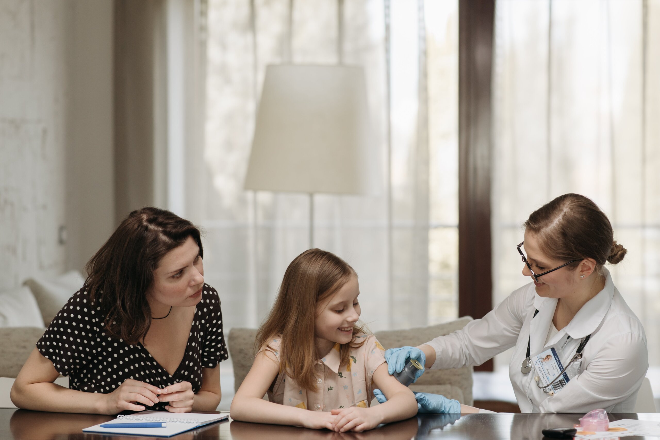 A health care professional sitting at a table with a mother and daughter