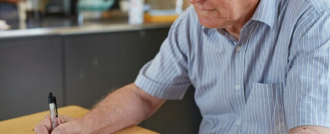 A man sitting at a table writing diabetes data in a notebook