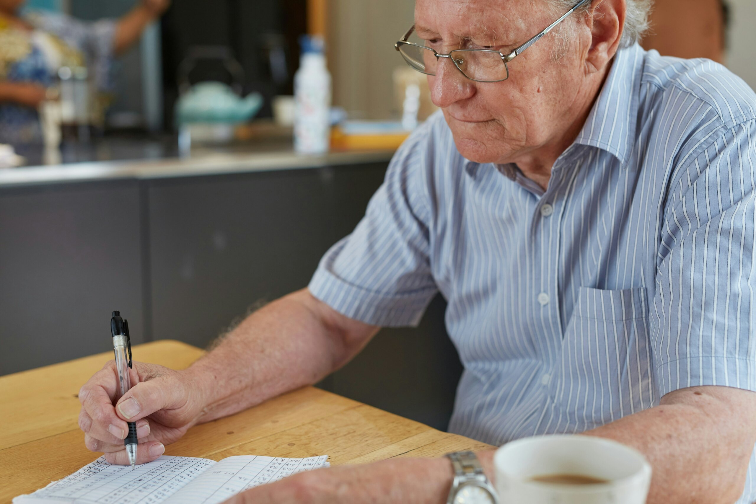 A man sitting at a table writing diabetes data in a notebook