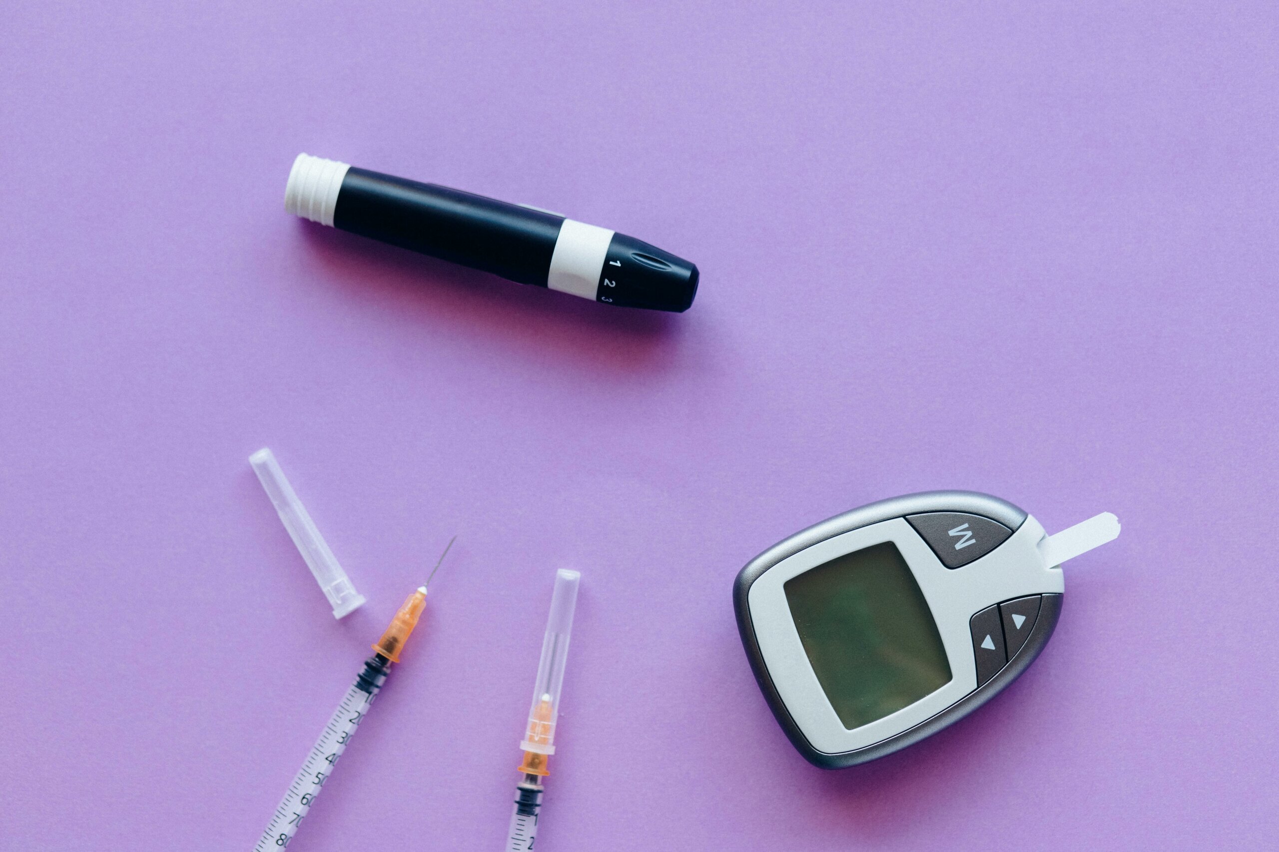 A variety of diabetes supplies on a purple background
